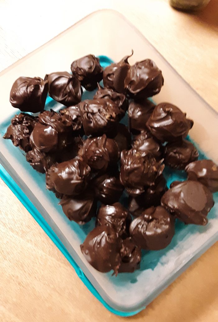 chocolate-coated date and peanut butter balls in a glass dish