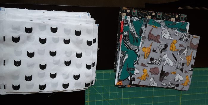 squares of fabric of different cat designs preppared for quilting