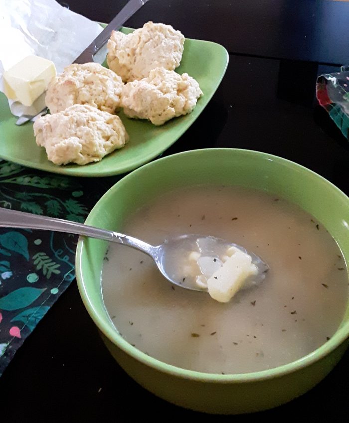 a bowl of soup next to a plate of biscuits