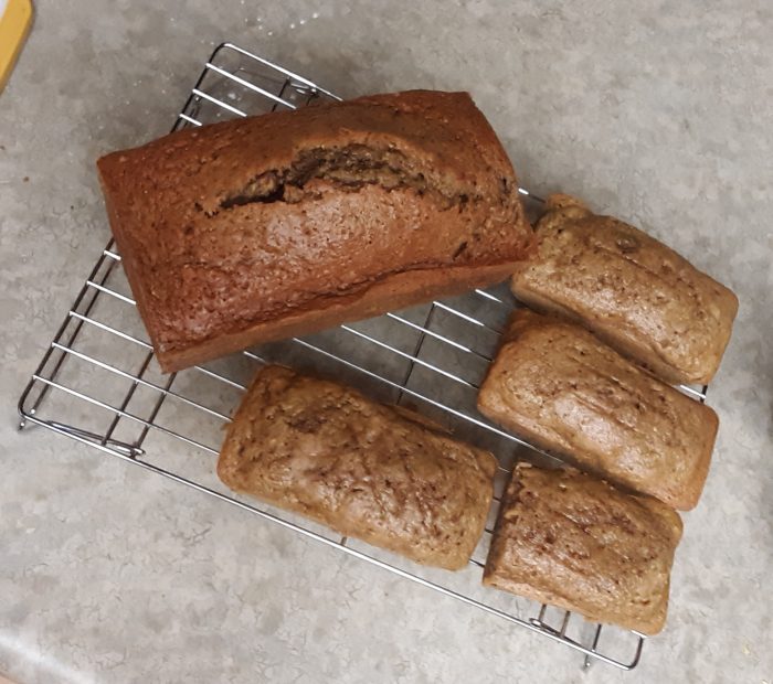 four small and one large zucchini bread on a wire rack