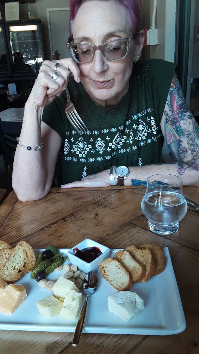 a woman with a fork in hand admiring a cheese board