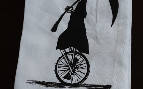 a white dishtowel with an image of the grim reaper riding a unicycle and the words "killin it"