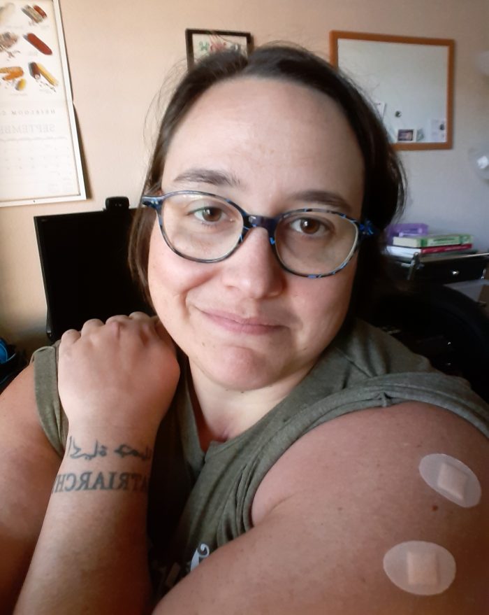 the author showing off her shoulder which has bandaids from getting shots