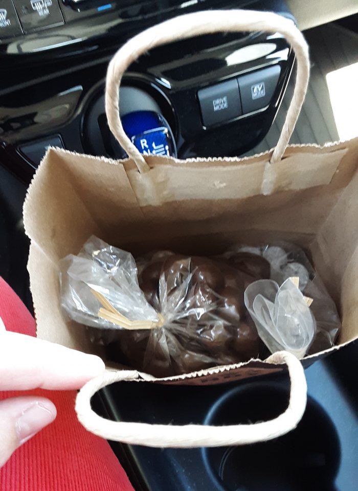 Several small bags of chocolates inside a paper bag
