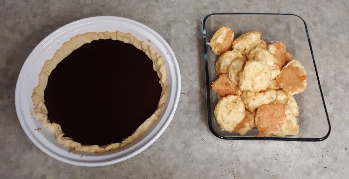 a chocolate tart in a round pie dish and cheese puffs in a glass dish