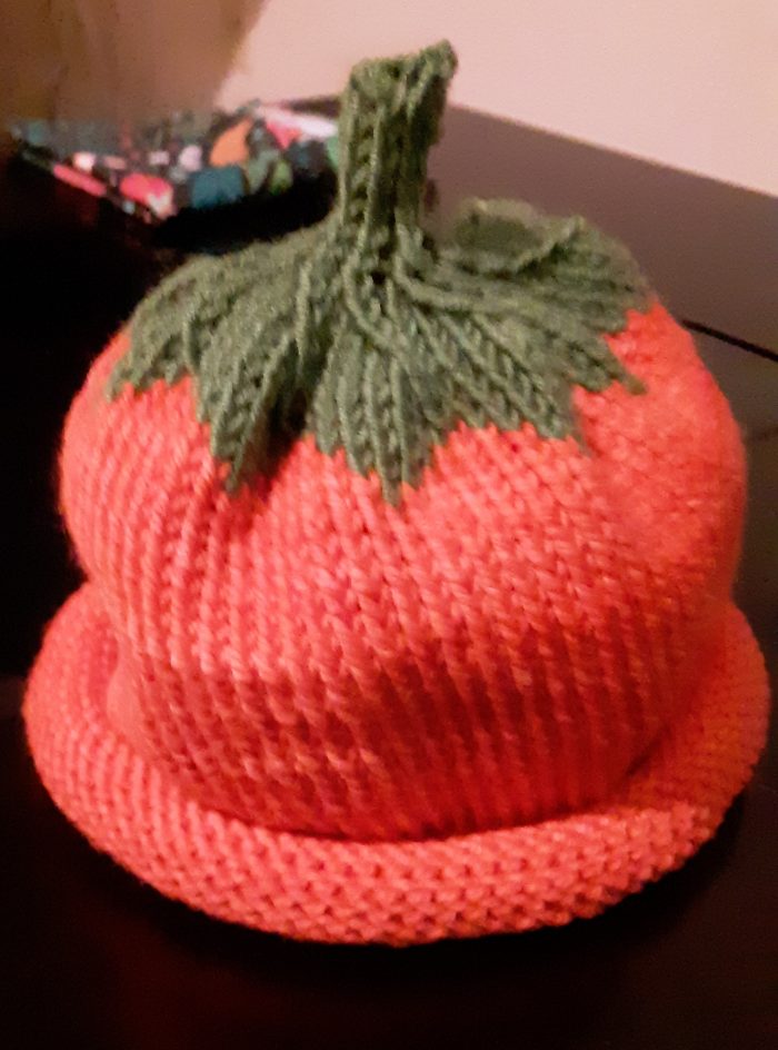 a knit cap, primarily orange with green "leaves" at the top