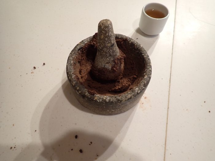 a mortar and pestle with beaten chocolate plus a small cup of tea