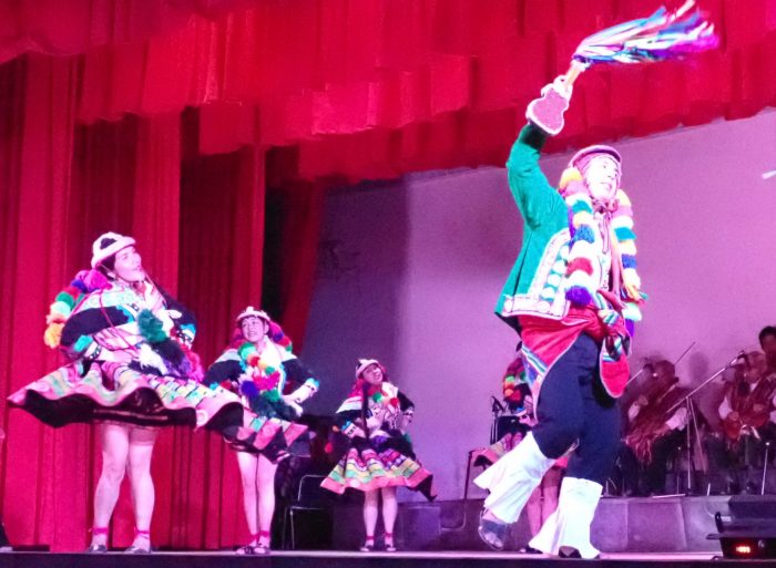 a scene from a folk dance with men and women in indigenous outfits