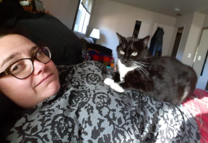 Huey the cat sitting on top of my stomach, me looking ruefully at the camera
