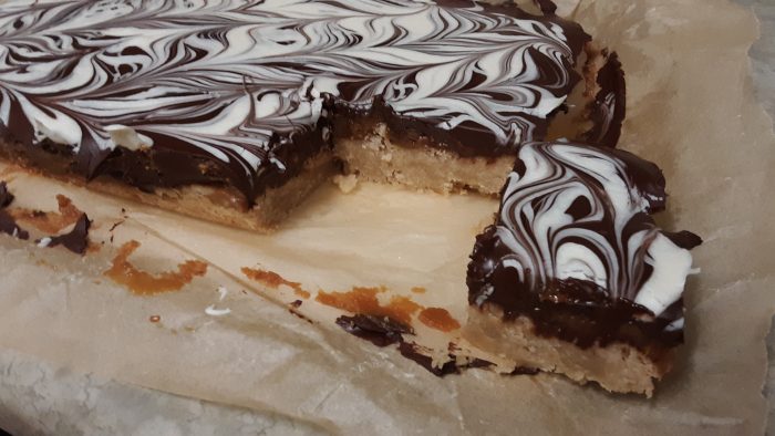 a piece of the millionaires shortbread cut out of the whole to show the layers inside