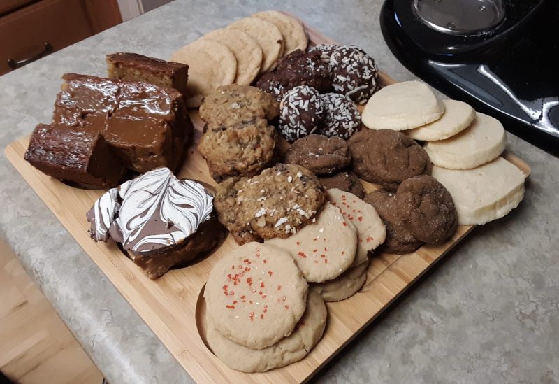 a wooden board covered in a variety of holiday cookies