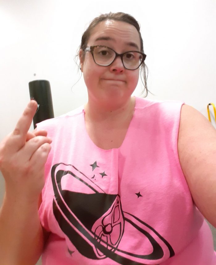 me at the gym, wearing a pink shirt with a ham planet on it and flipping off the camera