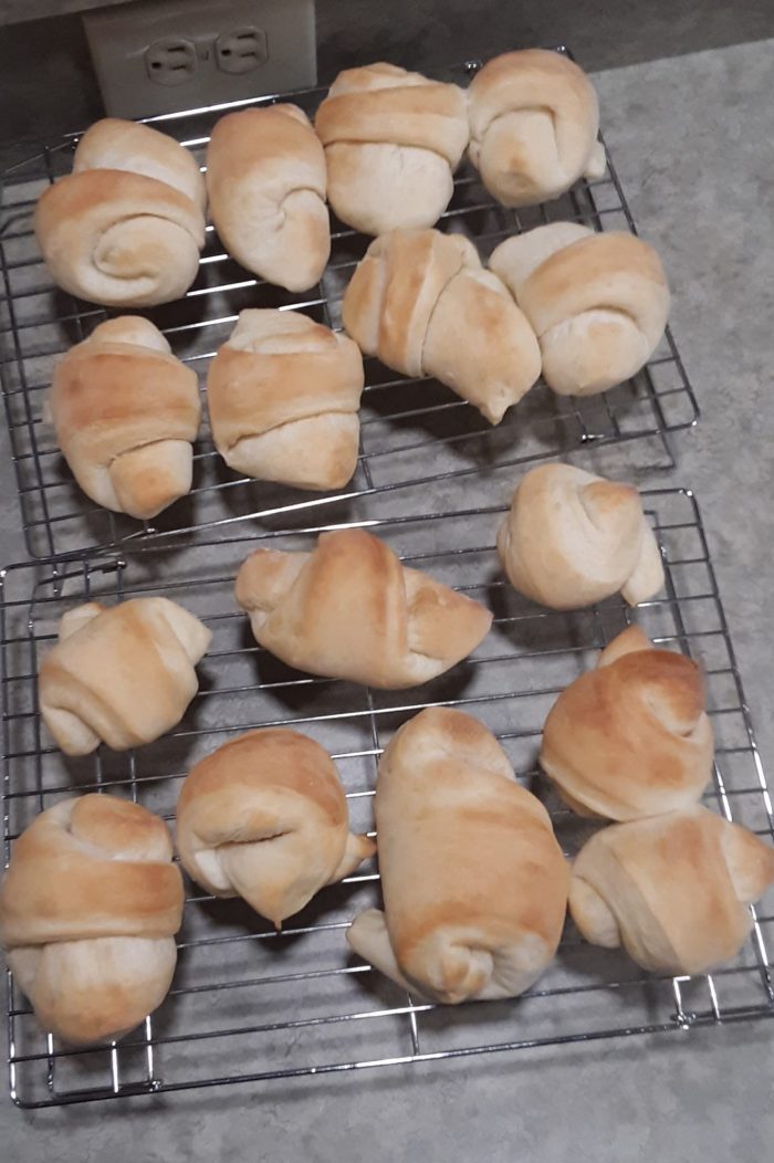 a batch of crescent rolls cooling on wire racks