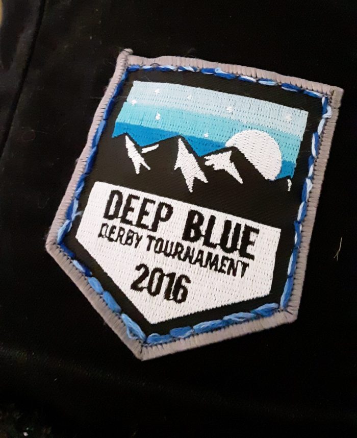 a patch that says "Deep Blue Derby Tournament 2016" stitched onto a black vest using backstitch