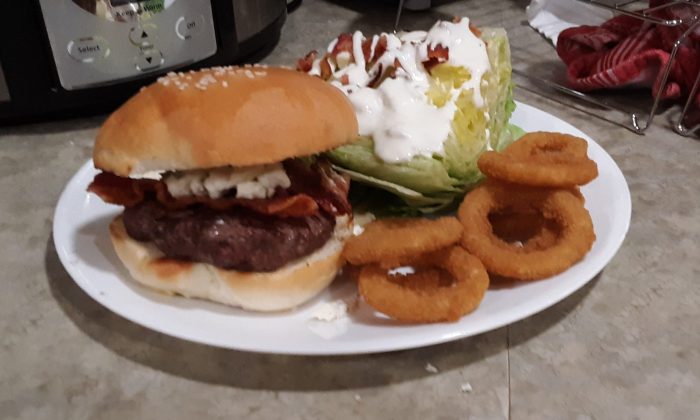 a plate with wedge salad, a blue cheese + bacon burger, and onion rings