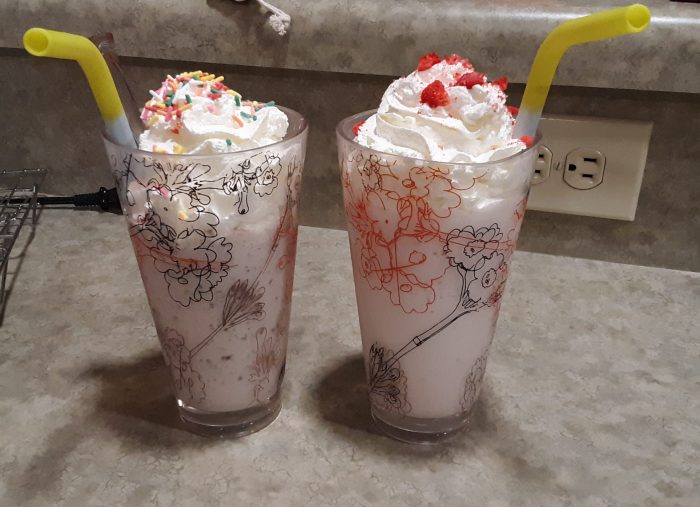 two homemade milkshakes topped with whipped cream