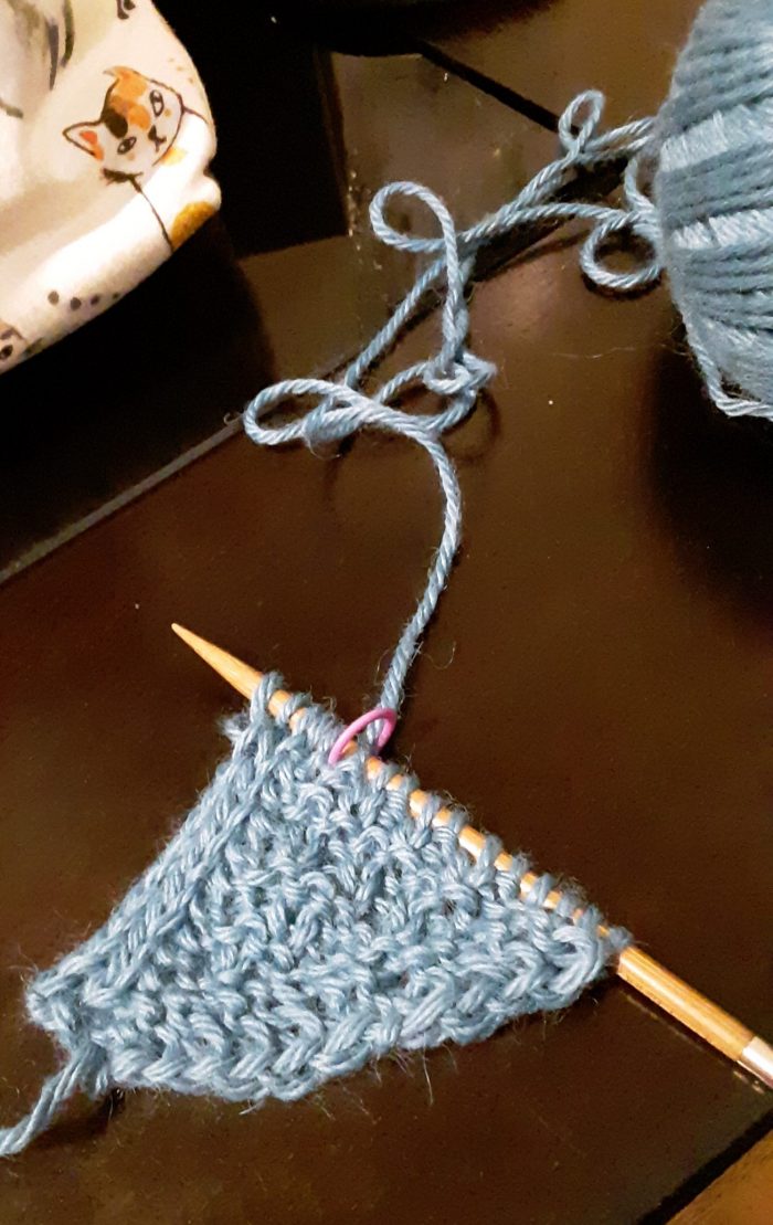a small piece of newly started knitting, so far a little triangle in blue yarn