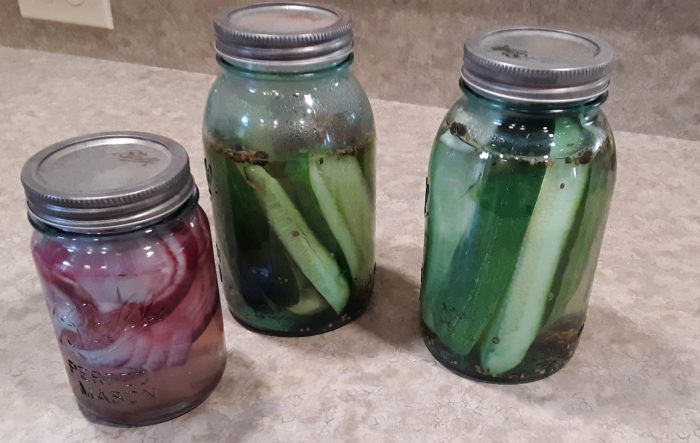 two jars of pickles and a jar of pickled onion