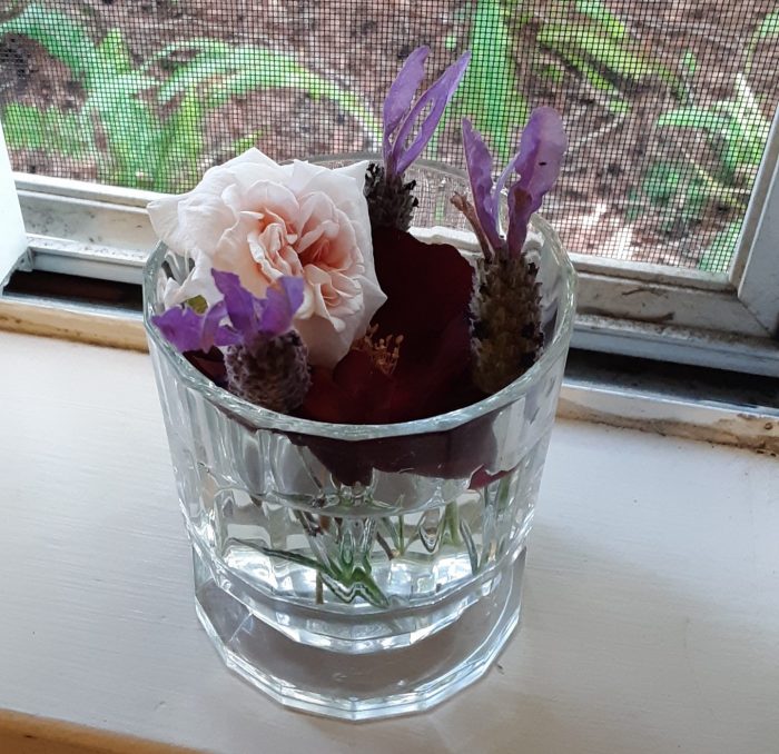 Tiny flower arrangement in a drinking glass