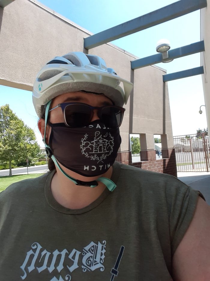 me in a bike helmet and a face mask that says "village witch"