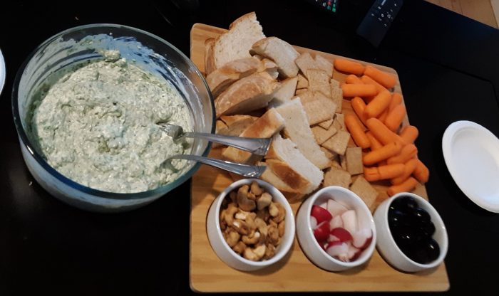 spinach dip with an arrangement of bread, veggies and other snacks