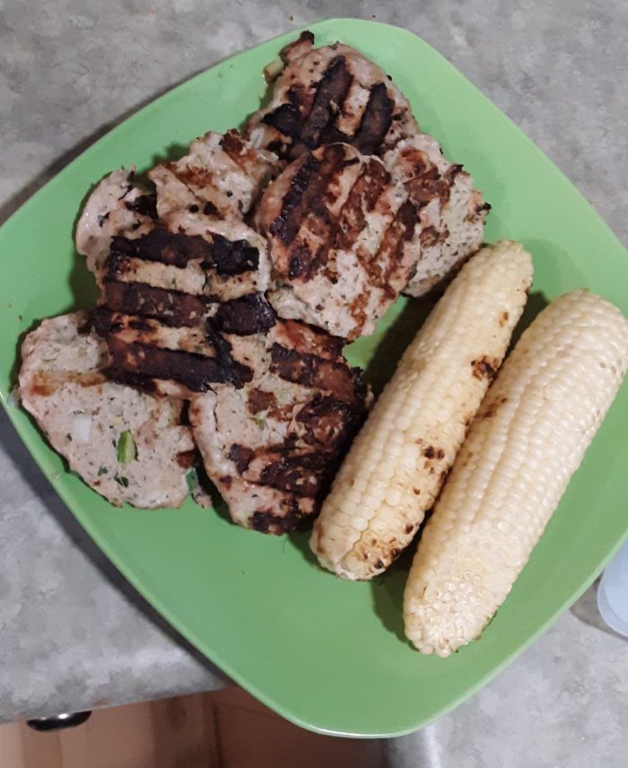 a plate of grilled turkey burgers and corn