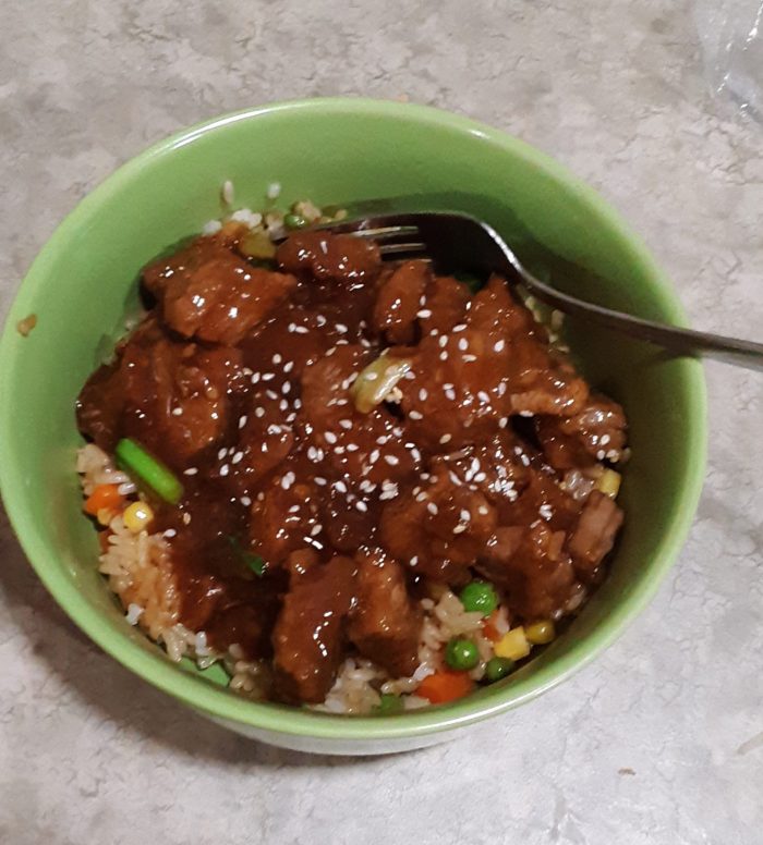 mongolian beef in a bowl on top of fried rice