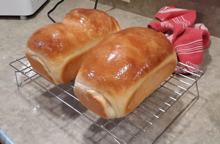 two loaves of potato bread cooling on a wire rack