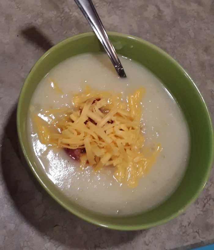 a bow of potato soup topped with bacon and cheese