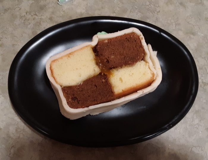 A slice of battenberg cake on a small plate.