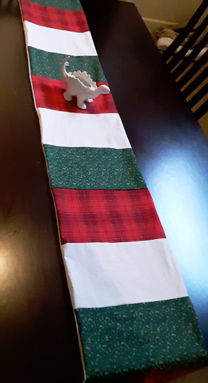 A table runner in alternating blocks of red, green, and white fabric