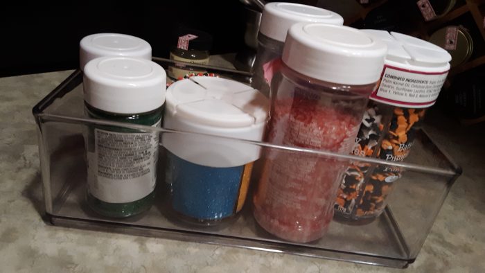 a small plastic bin holding six different jars of sprinkles