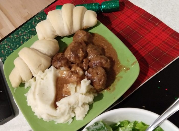 A plate with crescent rolls, mashed potatoes, and swedish meatballs