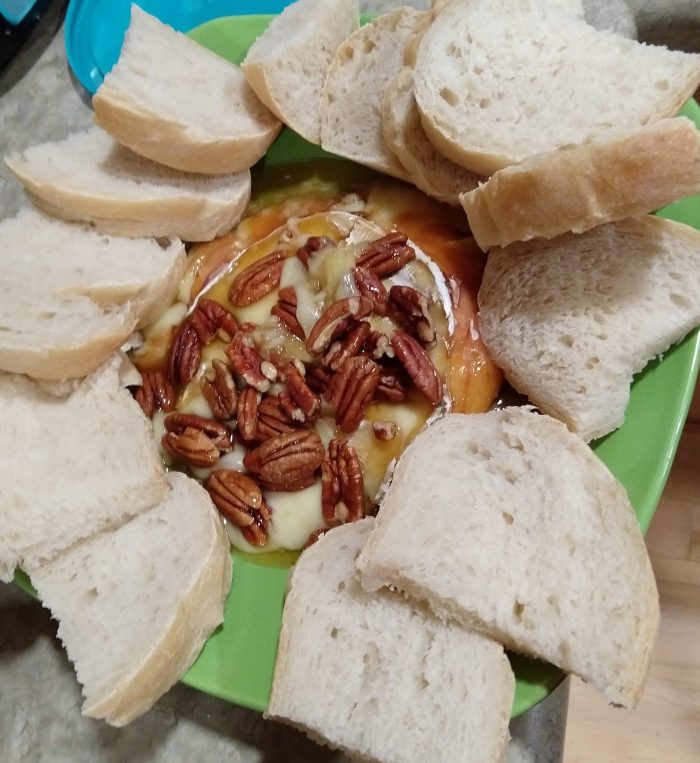 baked brie topped with honey and pecans, surrounded by slices of bread