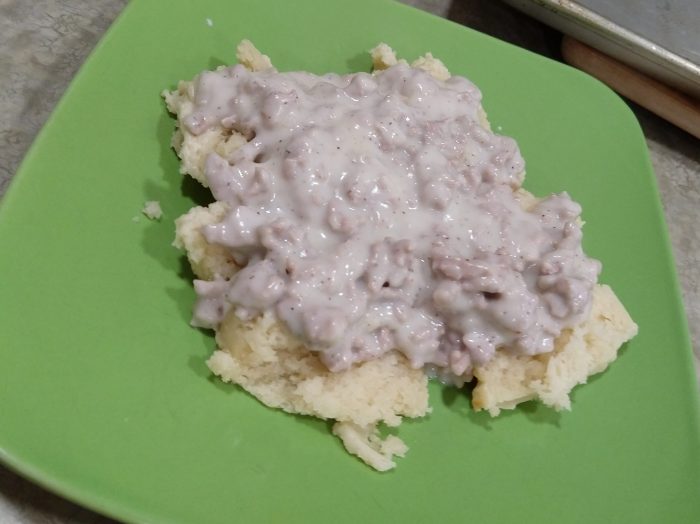 a plate with two biscuits covered in a pork gravy