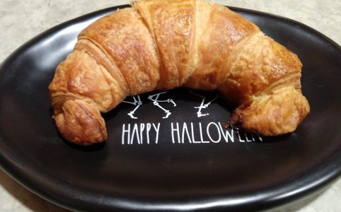 a single croissant on a small black plate
