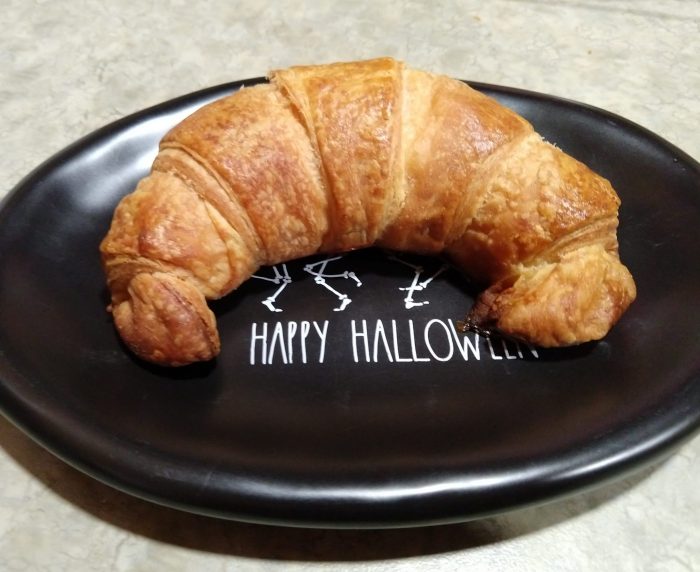 a single croissant on a small black plate