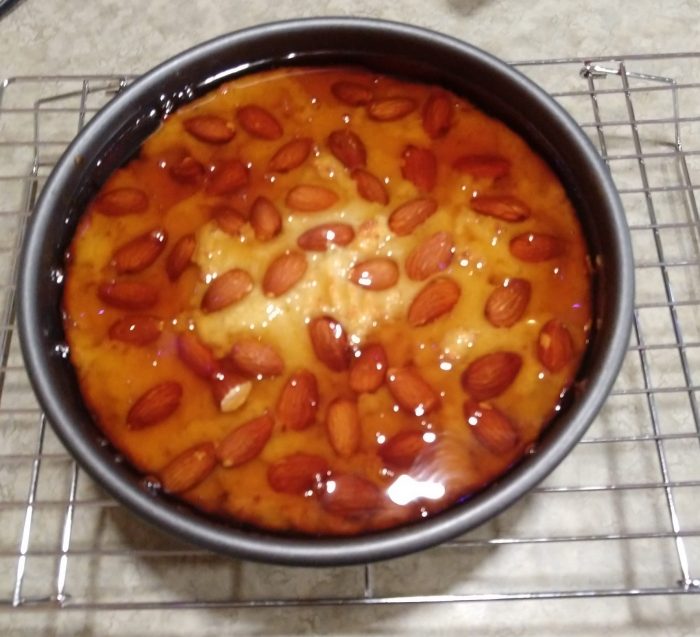almond-topped semolina cake in the pan, covered with a large quantity of syrup to seep into the cake