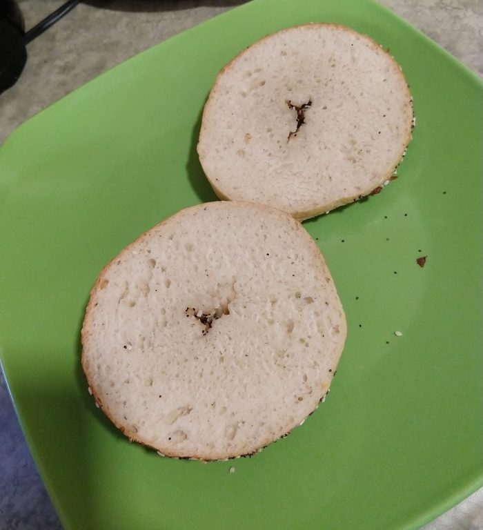 bagel cut in half to show the interior texture, resting on a green plate