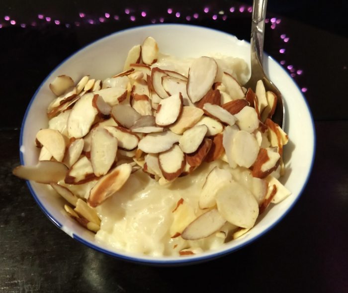 a small bowl of rice pudding topped with sliced almonds