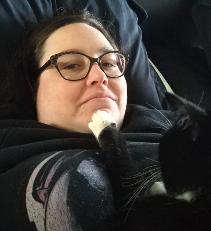 me, looking at the camera with a sort of "is this my life" skeptical face. Huey, whose head is seen from behind, has her white paw resting on my chin