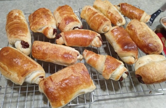 two wire racks covered in chocolate croissants that are cooling after baking