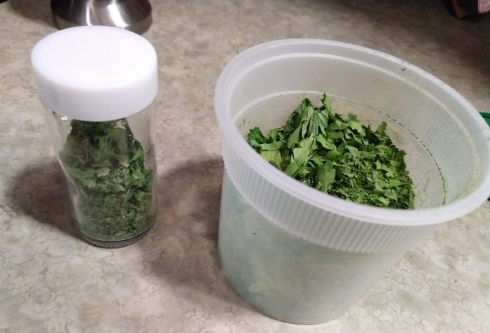 a spice jar of dried cilantro and a small tupperware full of dried parsley