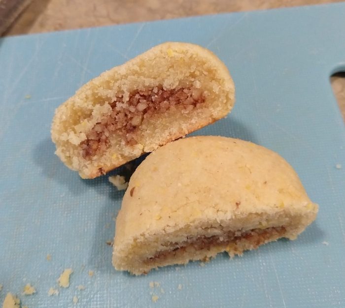 cross-section of a ramadan nut cookie, showing a crumbly texture and a walnut mixture inside