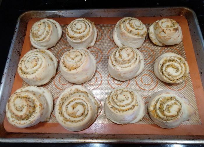 a sheet pan with 12 rolls, spirals full of cheese and onion