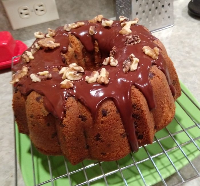 a bundt cake topped with chocolate ganache and walnuts