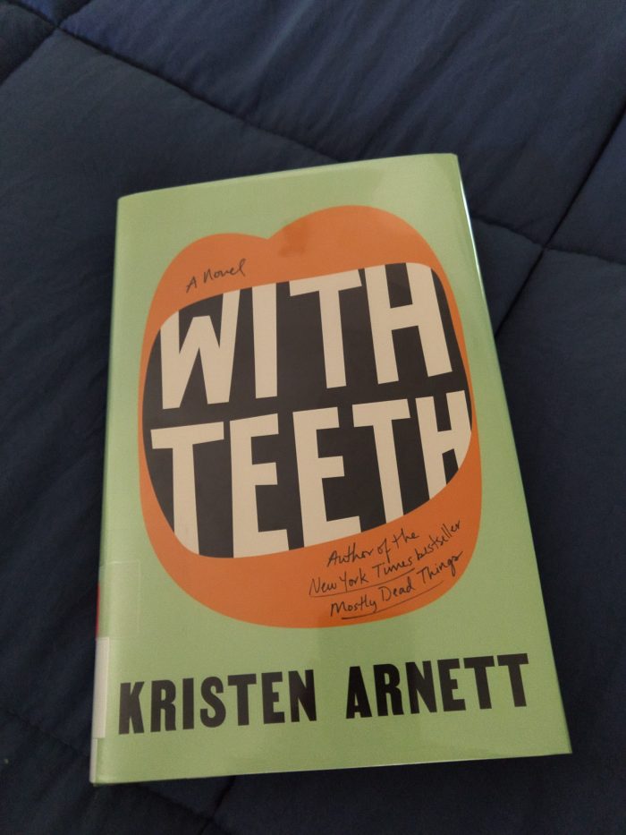 hardback book: With Teeth. Cover is light green. There is a stylized mouth wide open and the title of the book is inside to look like teeth