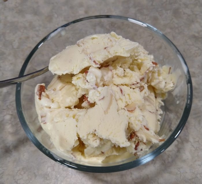 a small bowl filled with a creamy, golden ice cream with slivered almonds mixed in