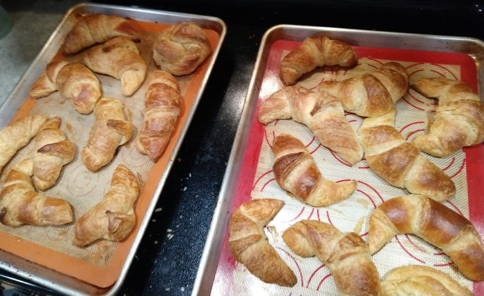 two sheet pans of freshly baked croissants
