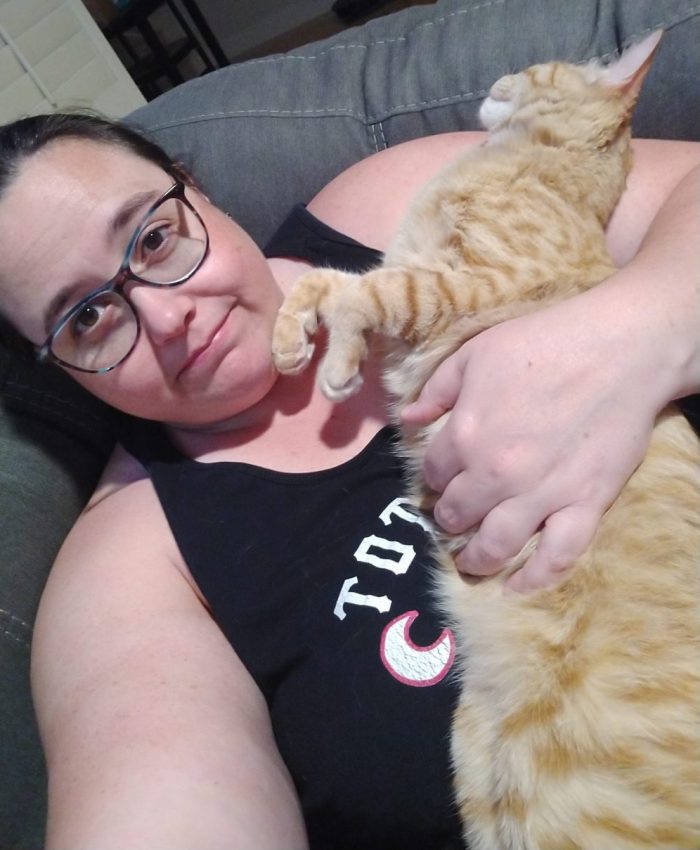 me on the couch, Fritz the cat in my arm. He is stretched out and his back legs are not in the frame, making it look like he goes on forever